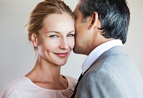 Man whispering to smiling woman
